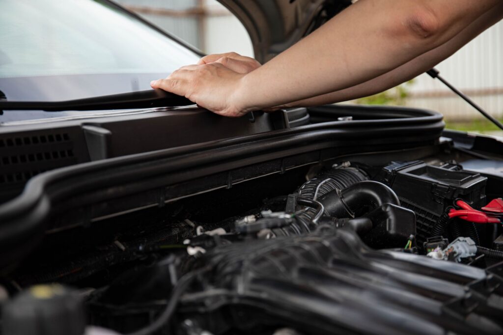 A close-up of a mechanic inspecting a car engine, highlighting the importance of car maintenance for emergency towing Las Vegas