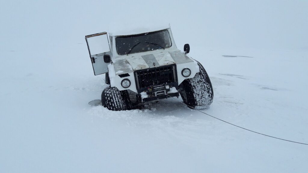 A recovery expert using a winch to pull a stuck vehicle out of sand. — off road towing las vegas